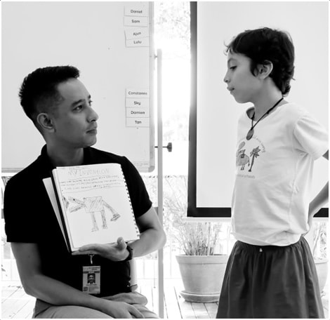 A student discussing his invention idea with his teacher